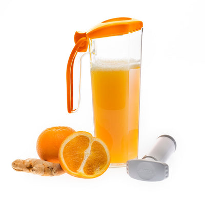 Foto eines 1-Liter-Saft-Vakuumbehälters mit Griff, zu 3/4 mit Orangensaft gefüllt. Neben dem Behälter befinden sich eine ganze Orange, eine halbe Orange mit einem Stück Ingwer und die kleine Handpumpe.