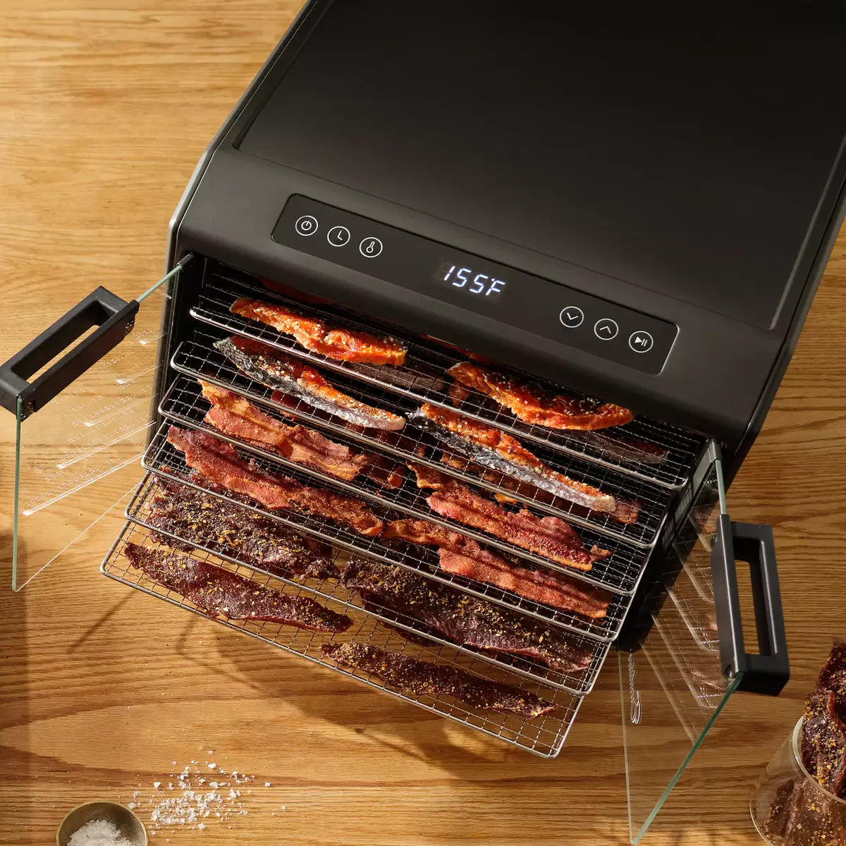 Geöffneter Excalibur Dörrautomat von oben mit dörrendem Bacon auf den Edelstahlgittern bei 155°F.